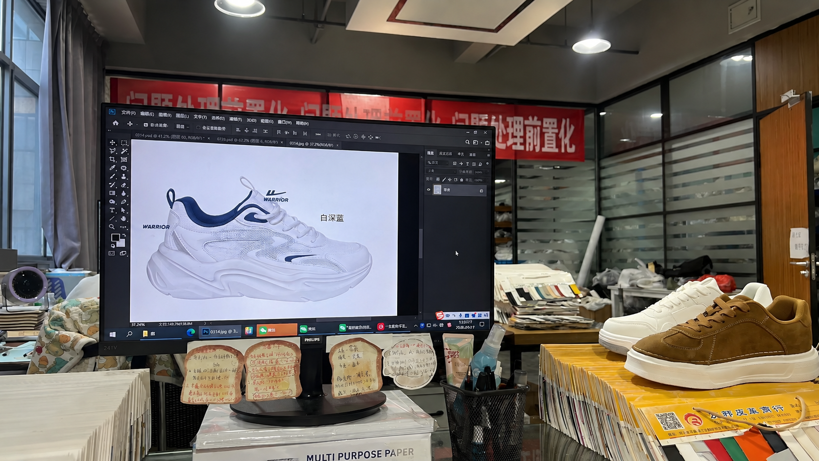Design studio with sneaker CAD on screen and sample shoes